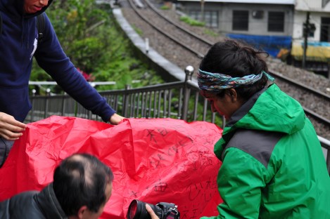 quickly placing mouth of ballon on ground so hot air will fill it../pingxi, taiwan/jan 2013